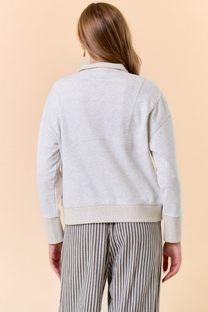 Woman wearing a light gray sweater and striped pants on a beige background