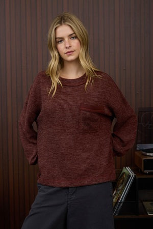 Person wearing a maroon sweater in an indoor setting