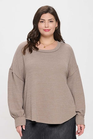 Woman wearing a beige sweater against a white background