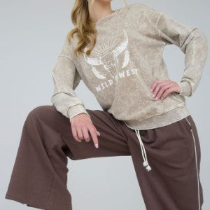 Person wearing a beige sweatshirt with a graphic design and text, sitting on a light gray background.