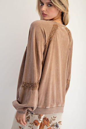 Woman wearing a brown sweater with lace details on a white background