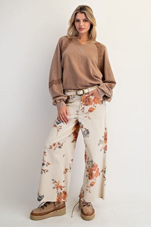 Woman wearing a brown top and floral pants on a white background