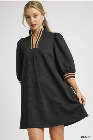 Woman wearing a black dress with striped cuffs on a light gray background