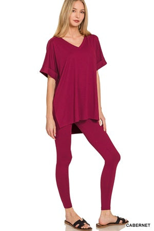 Woman wearing a burgundy top and leggings on a white background