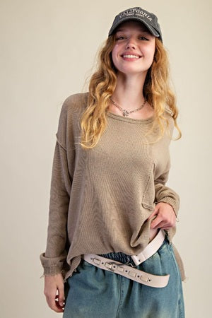 Woman wearing a beige sweater and blue cap with a neutral background