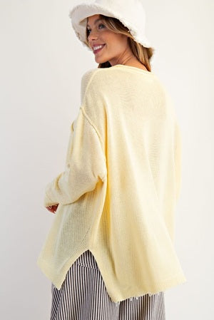 Woman wearing a light yellow cardigan over a striped dress on a white background