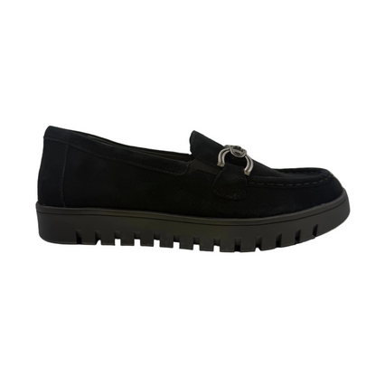 A black slip-on loafer-style shoe with a textured sole and a metallic ring detail on the vamp.