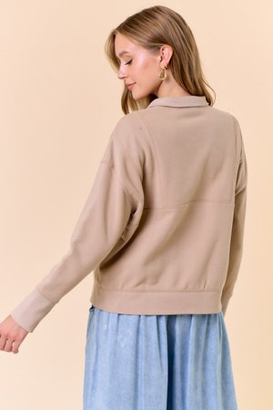 Woman wearing a beige sweater over a blue dress on a beige background