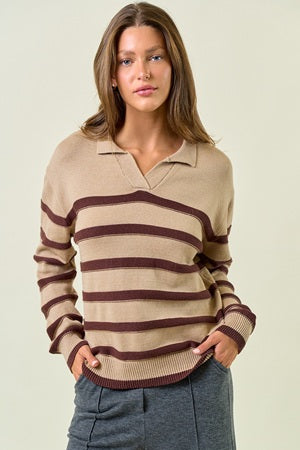 Woman wearing a beige and brown striped sweater against a plain background