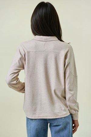 Person wearing a beige long-sleeve shirt with a neutral background