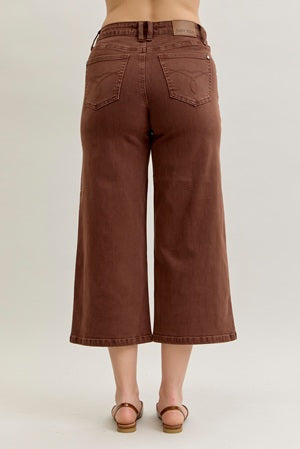 Brown wide-leg jeans worn by a person on a plain background