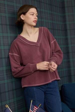 Woman wearing a maroon sweater against a plaid curtain background