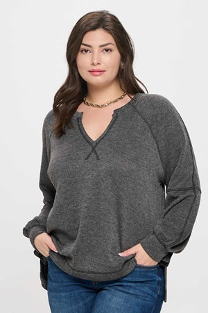 Woman wearing a gray long-sleeve top with a V-neckline on a white background