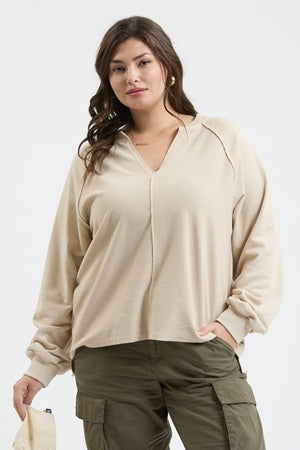Woman wearing a beige split neck top and green cargo pants on a white background