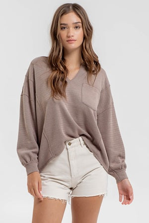 Woman wearing a brown oversized sweater and white shorts on a white background