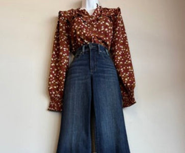 Brown patterned blouse and blue jeans on a mannequin against a white background