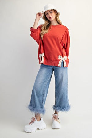 Woman wearing a red sweater with white bows and blue jeans on a white background