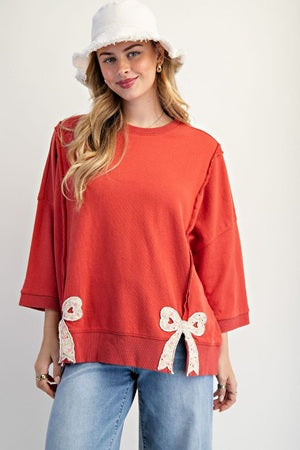 Woman wearing a red top with lace details and blue jeans on a white background