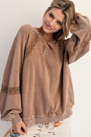 Woman wearing a brown sweater with lace details on a white background
