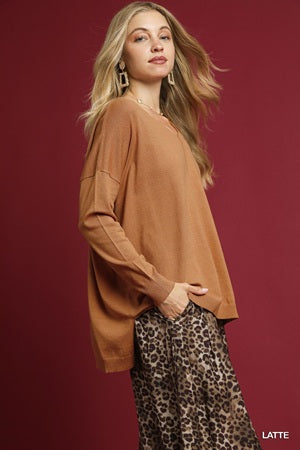 Woman wearing a brown sweater and leopard print pants against a red background