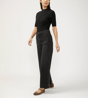 Person wearing a black top and dark jeans on a white background