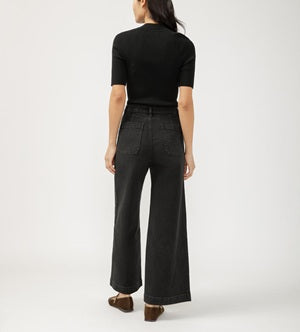 Person wearing black high-waisted jeans and a black top on a white background