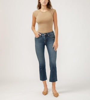 Woman wearing a beige top and blue jeans on a white background