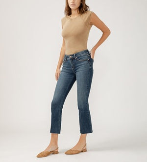 Woman wearing a beige top and blue jeans on a white background