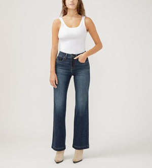Woman wearing a white tank top and blue jeans on a plain background