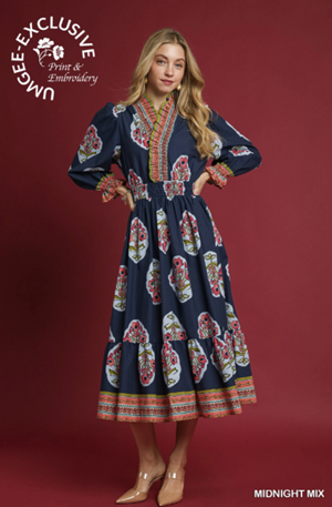 Woman wearing a navy dress with colorful floral patterns on a red background, featuring 'Meggie Exclusive' branding.