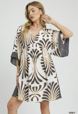 Woman wearing a patterned dress with bell sleeves on a white background