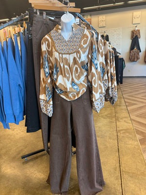 Mannequin wearing a patterned top and brown pants in a store setting