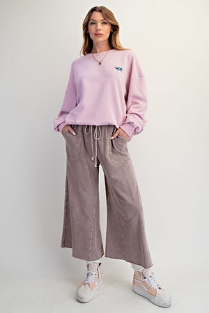 Woman wearing a pink sweatshirt and gray pants on a white background