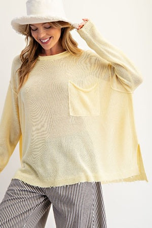 Woman wearing a light yellow sweater with a pocket and striped pants on a white background