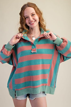 Woman wearing a striped sweater with pink and green horizontal stripes on a plain background